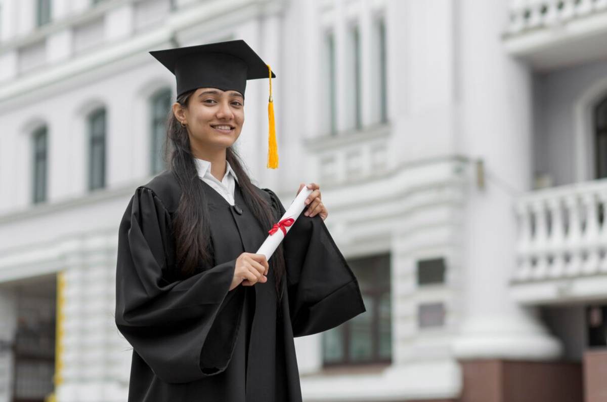 A woman in a graduation gown proudly holds her diploma, celebrating her academic achievement.