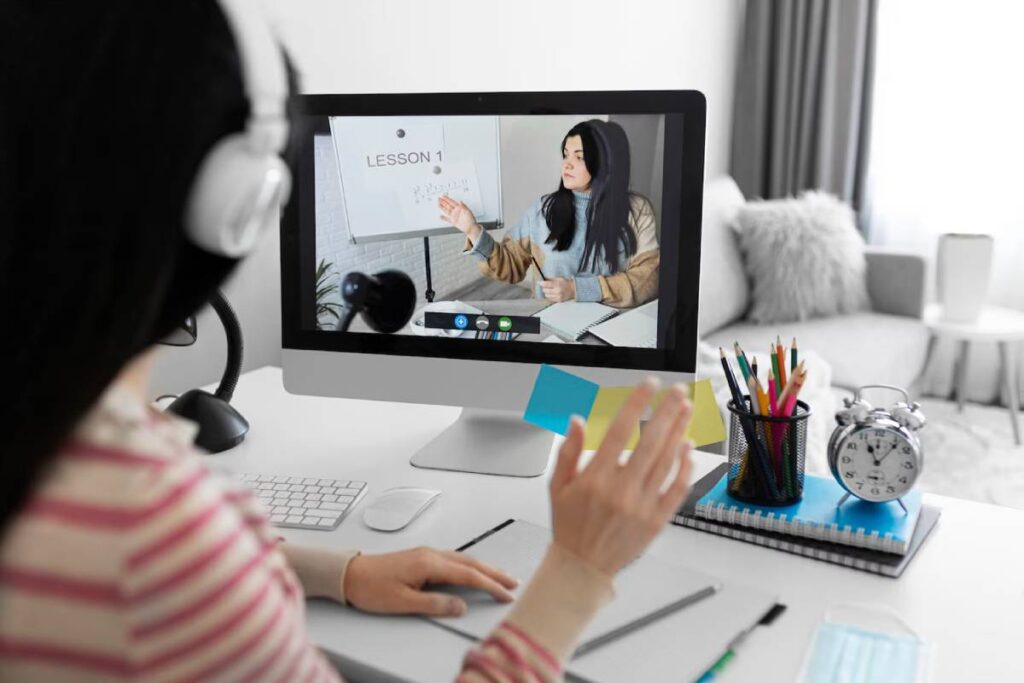 A woman sits at a desk with a computer and microphone, focused on her work.