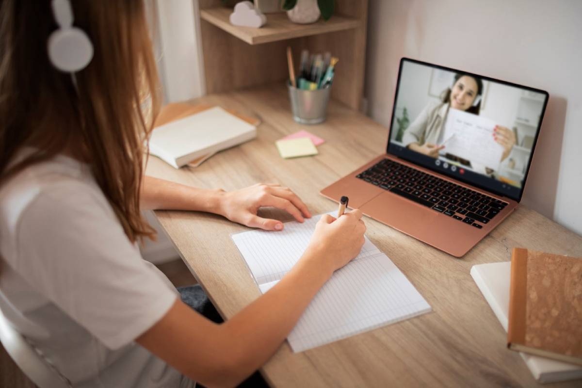 A woman engaged in a video call using both a laptop and a tablet, focused on her conversation.