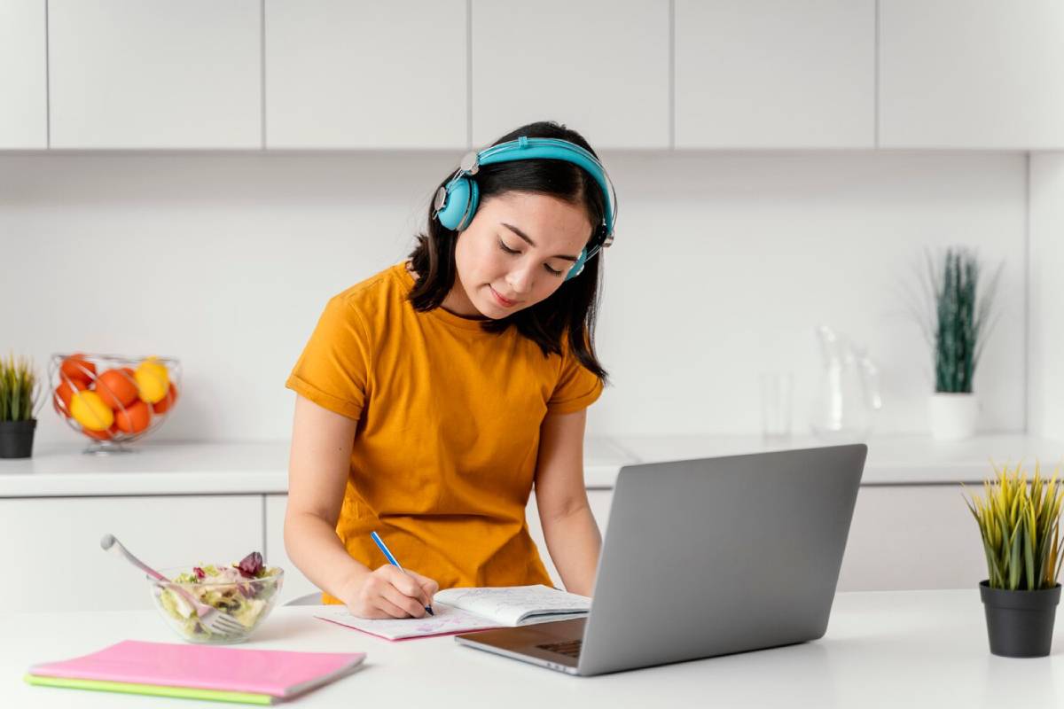 A woman with headphones is intently working on her laptop, immersed in her tasks.