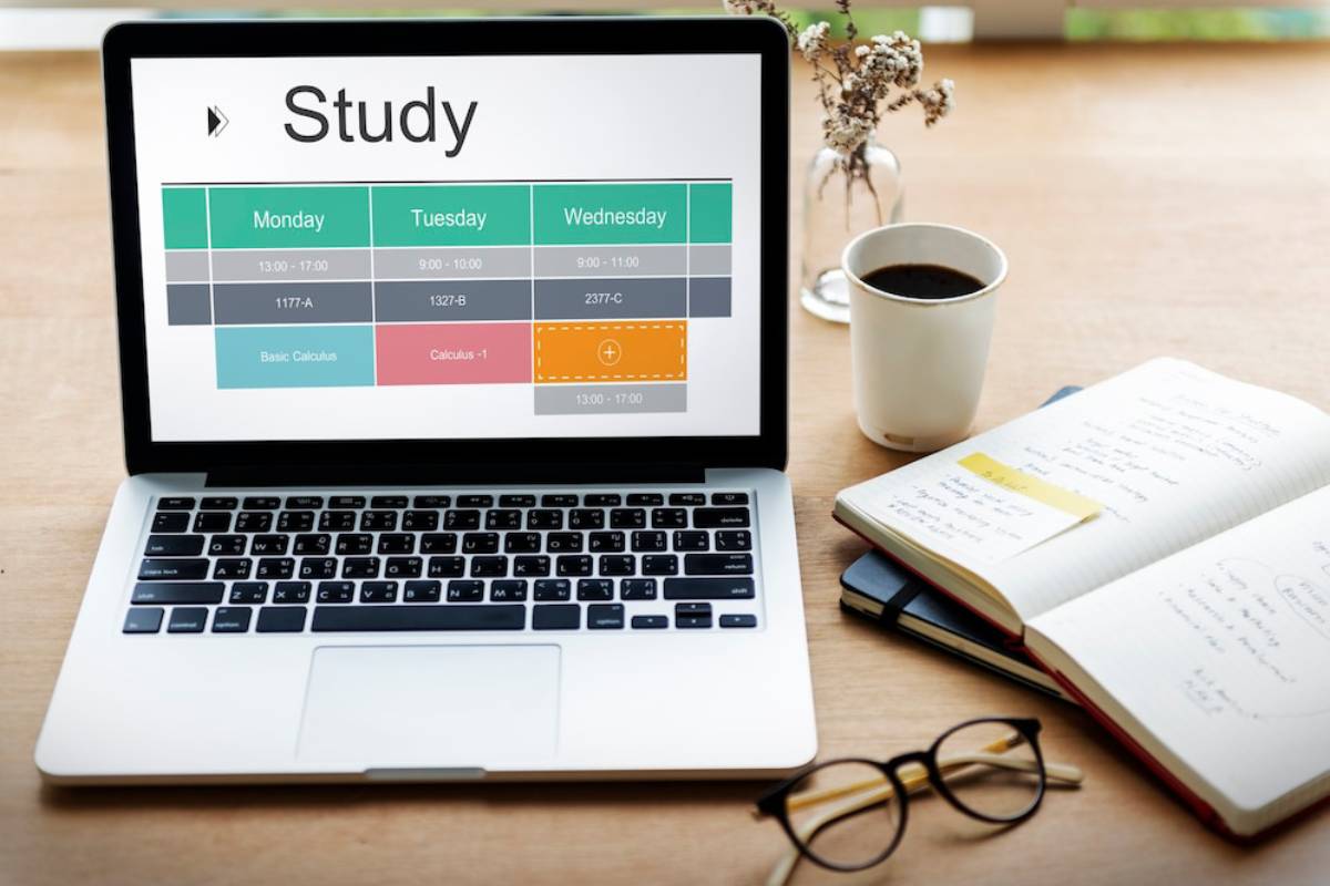 A laptop displaying study schedules, surrounded by notebooks and stationery, set up for an organized study session. 