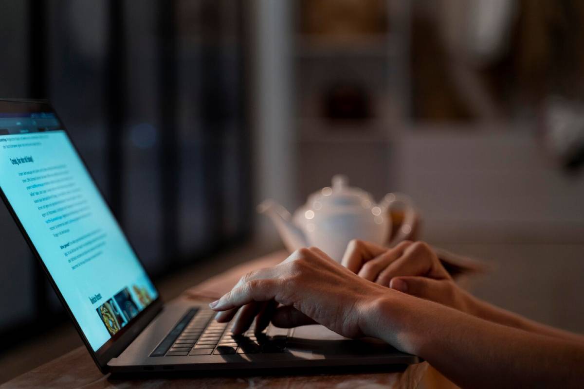 A person focused on typing on a laptop computer, with hands positioned over the keyboard.