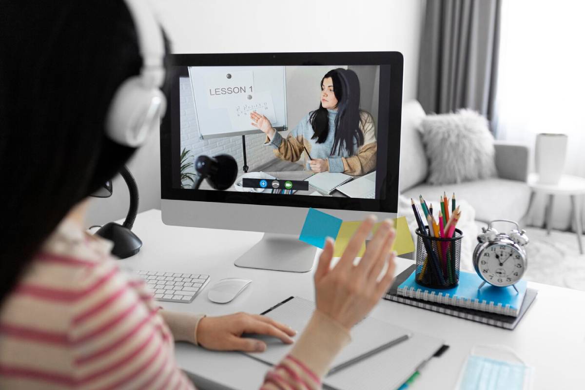 A woman sits at a desk with a computer and microphone, focused on her work.