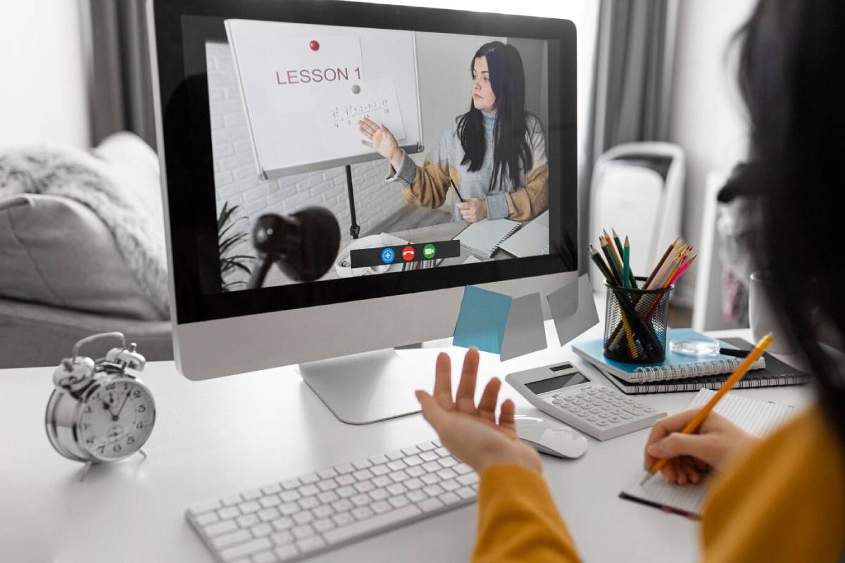 A woman watching online class on desktop and taking notes  
