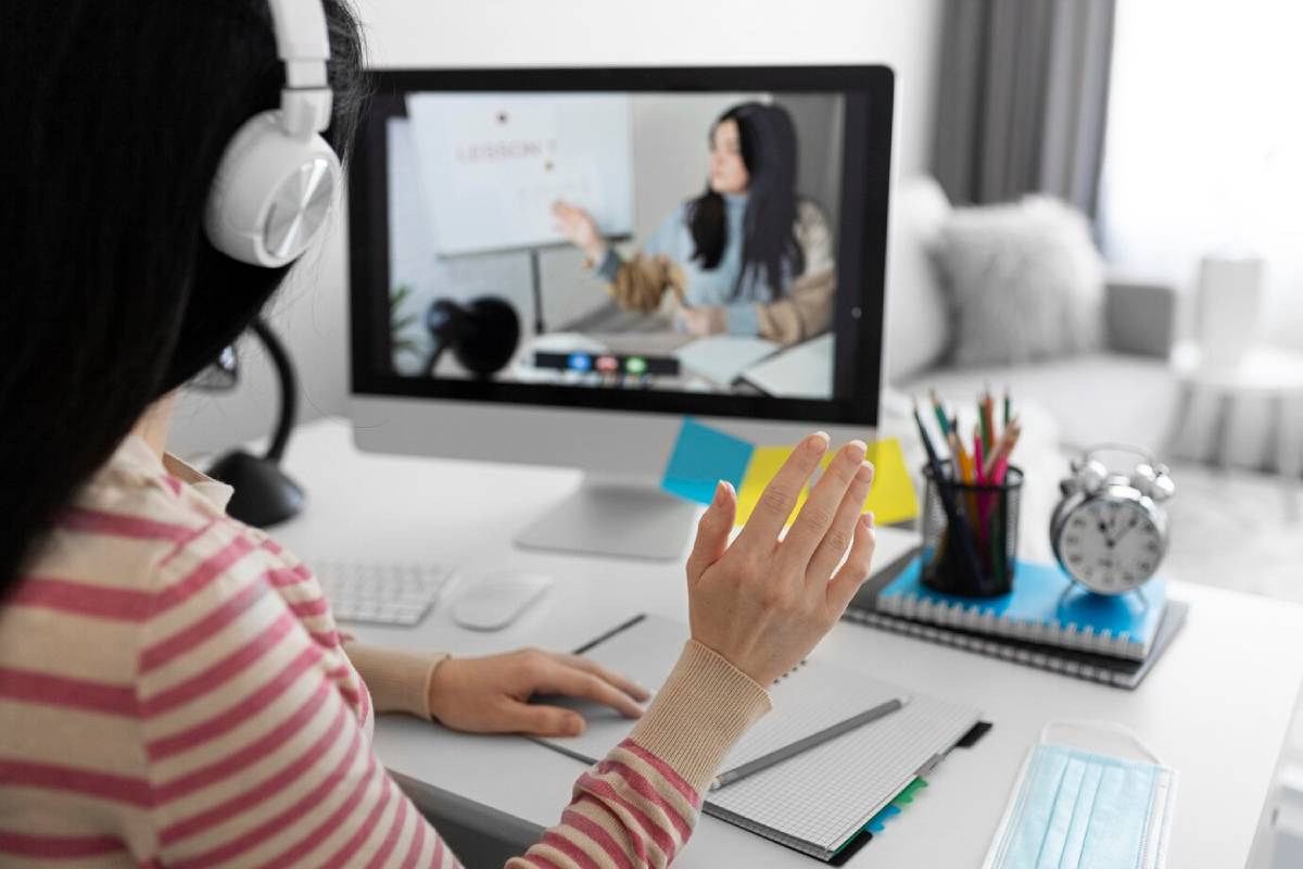 . A woman wearing headphones sits at a desk, focused on her computer screen.