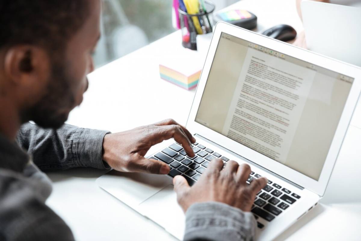 A man focused on typing on a laptop computer, with his hands positioned over the keyboard. 