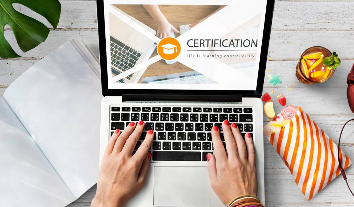  A woman types on a laptop displaying a certificate, focused on her work in a bright, modern workspace. 