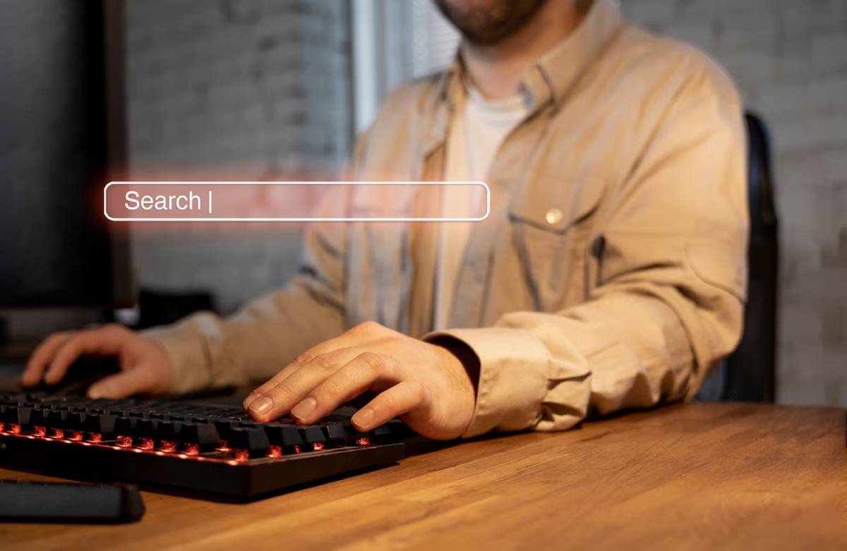 A man is focused on typing on a computer keyboard, with his hands positioned over the keys. 