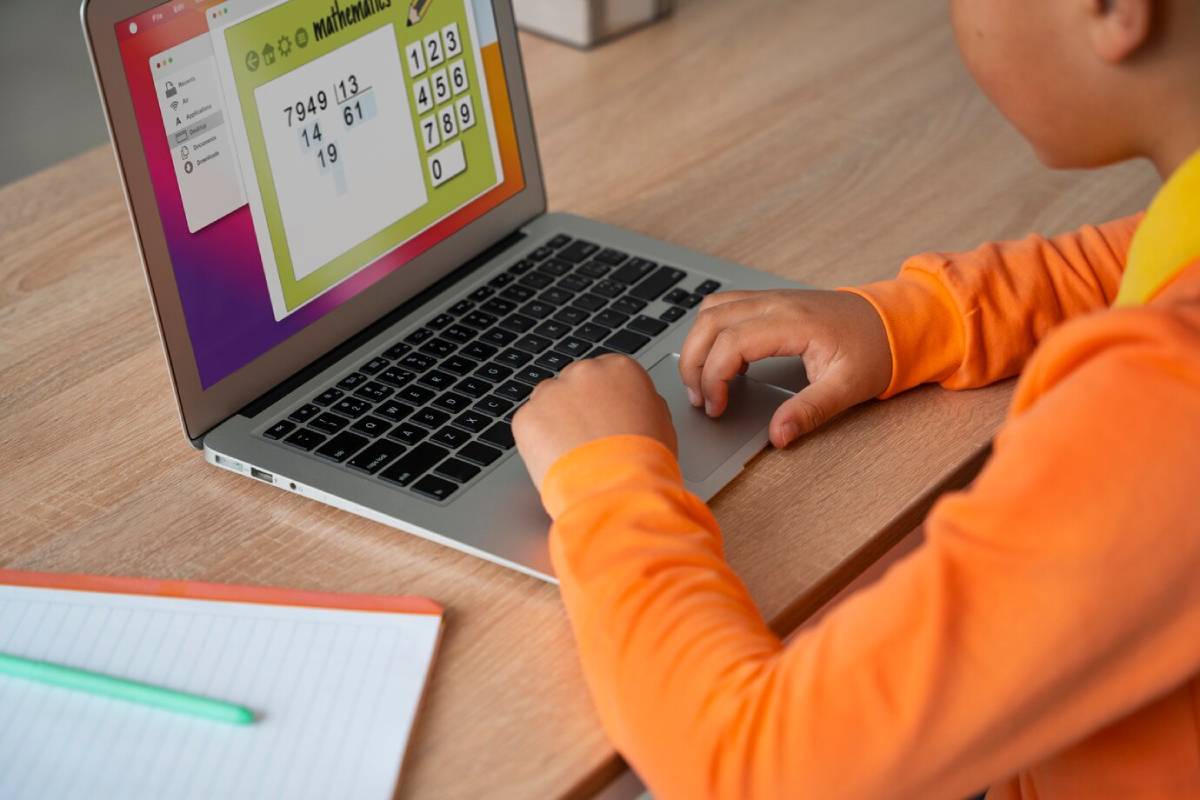A child focused on a laptop, solving a math problem with numbers and equations displayed on the screen.