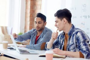 two boys are looking at laptop and discussing something