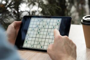 A person is playing Sudoku on a tablet.