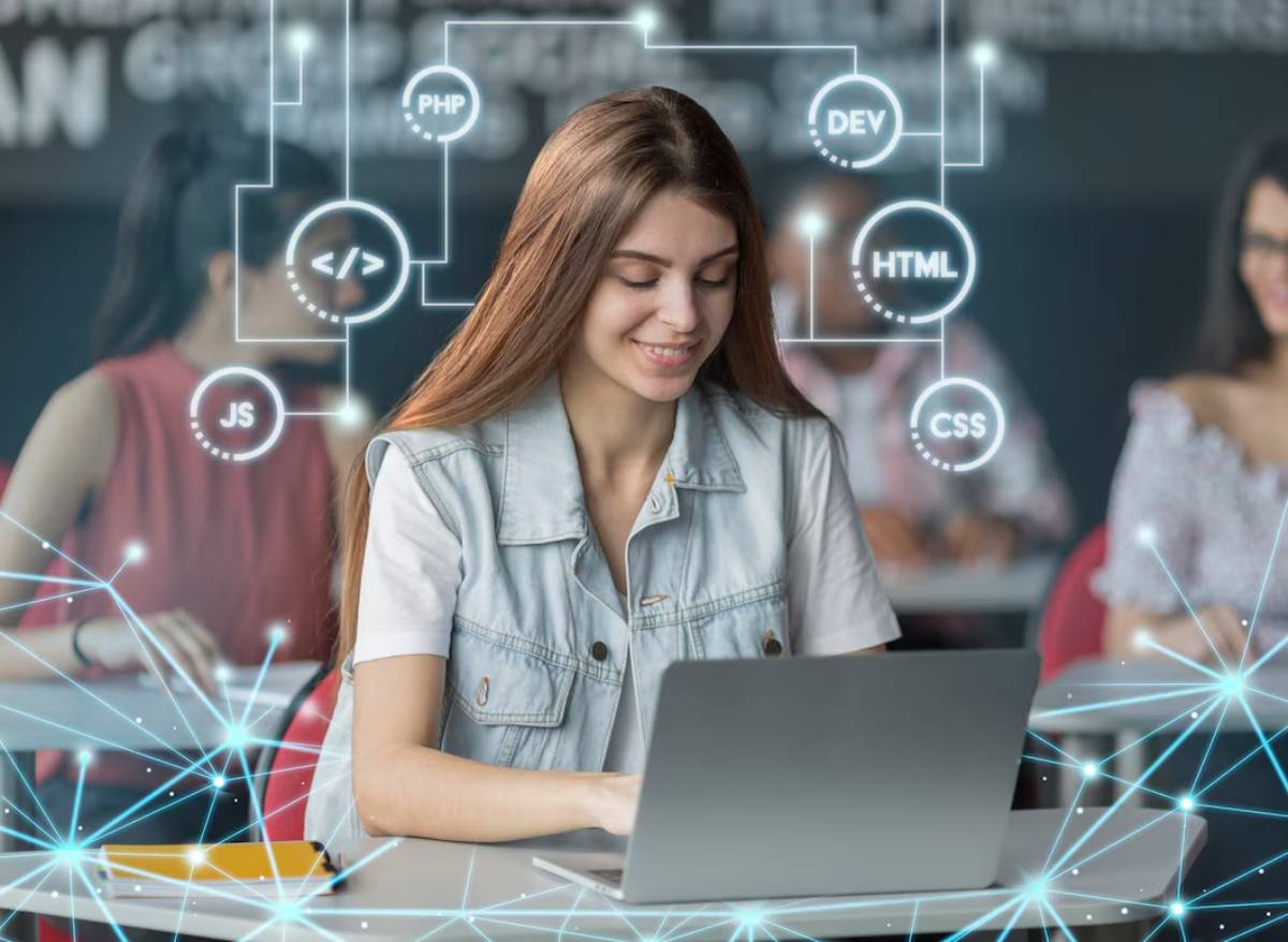 A student in a classroom, focused on a laptop, surrounded by digital icons representing coding languages like PHP, JS, HTML, and CSS.