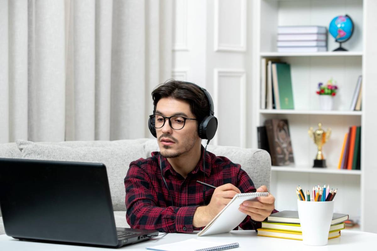  A man with headphones sits at a desk, focused on his laptop, creating a productive work environment. 