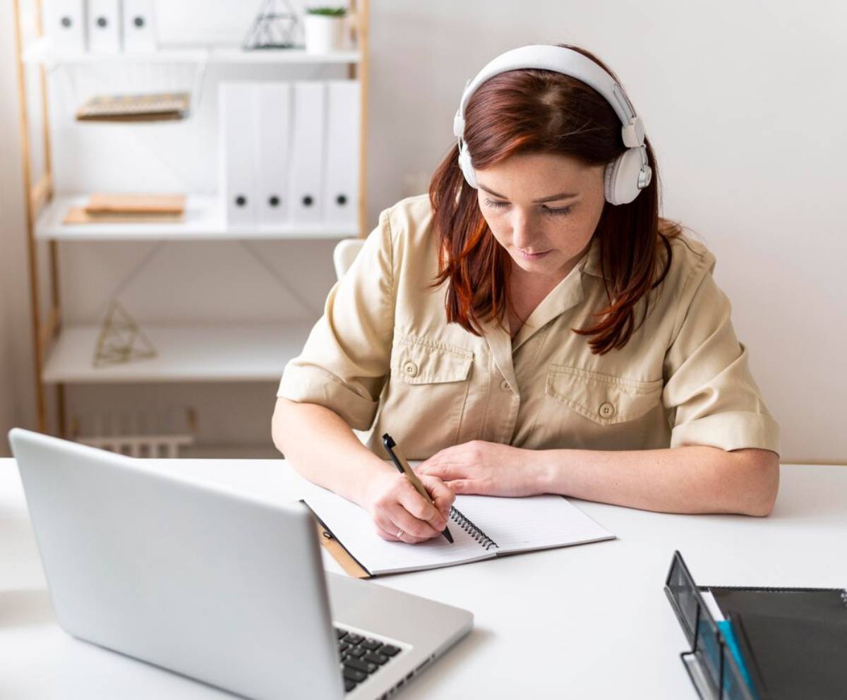 A woman with headphones is intently working on her laptop, immersed in her tasks. 