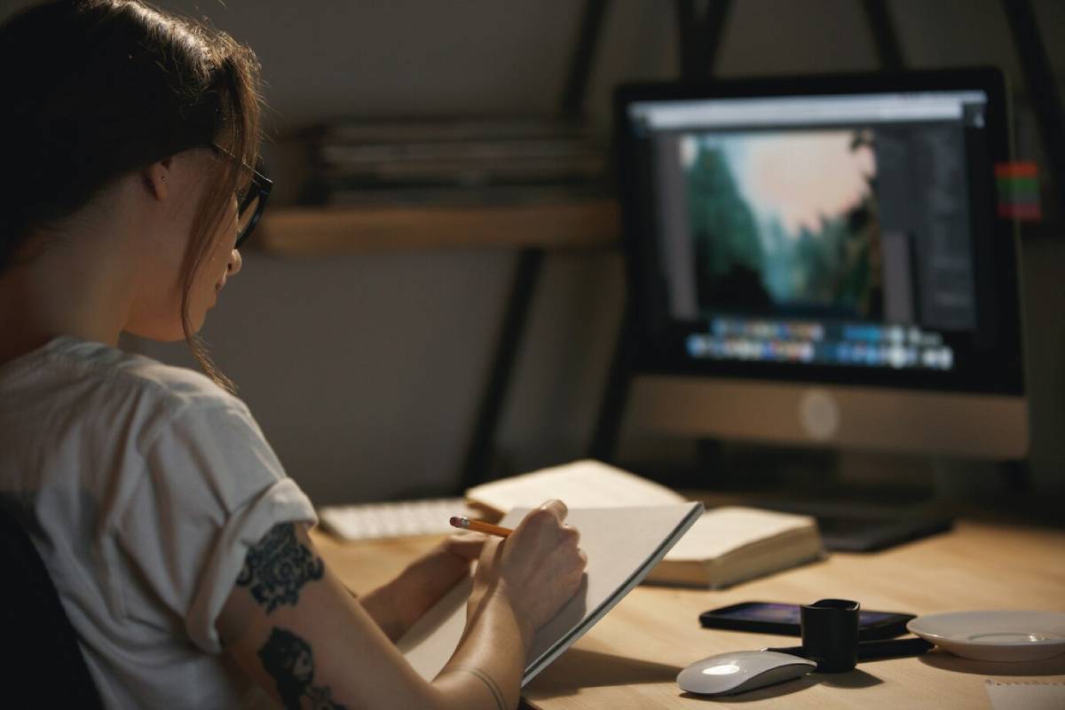 A woman engaged in computer work, seated in front of a monitor, concentrating on her tasks.