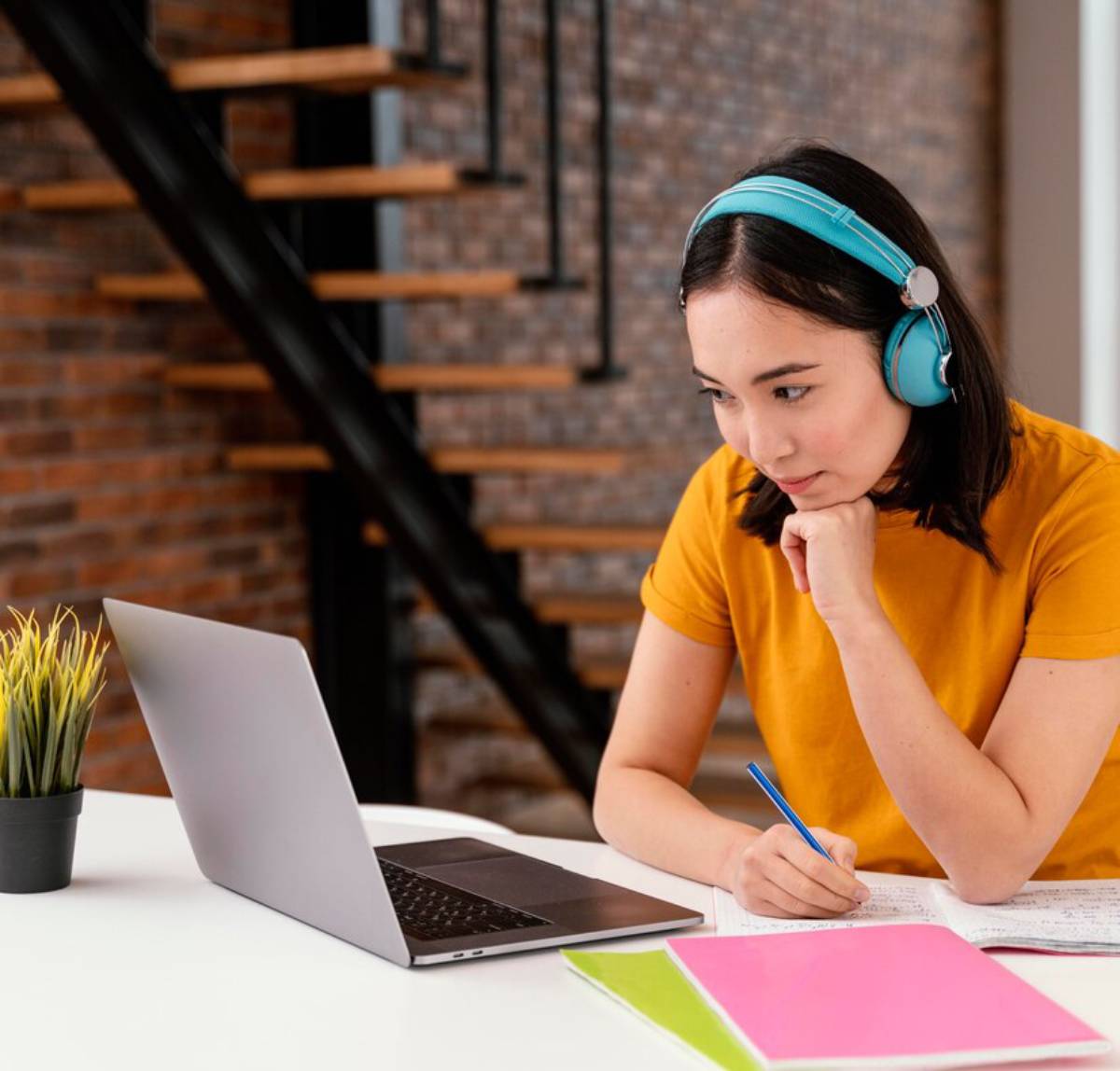  A woman wearing headphones is focused on her laptop, engaged in work.