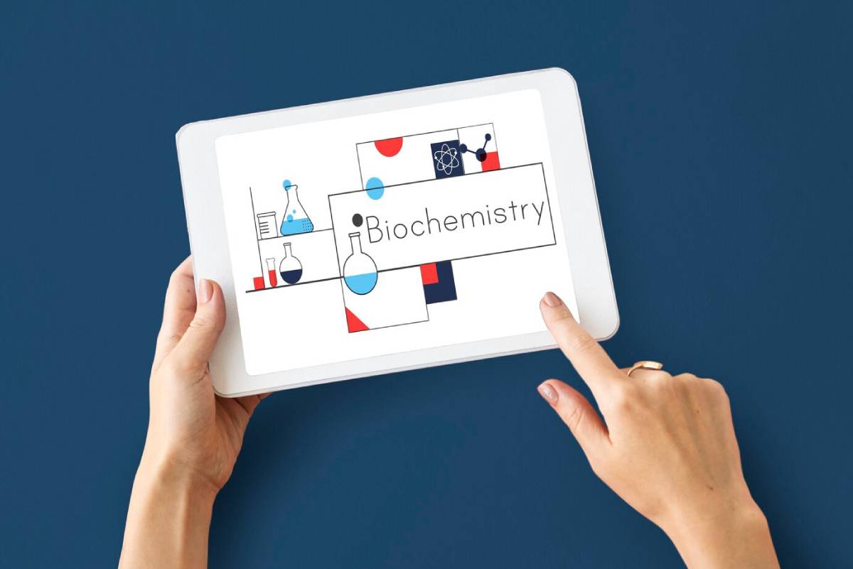 A hand holds a tablet displaying a colorful biochemistry-themed illustration with lab glassware and the text Biochemistry.